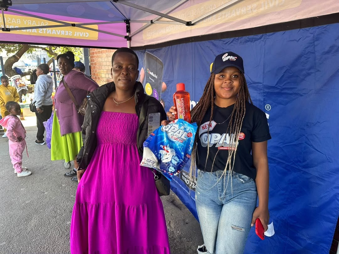A promoter handing an Opal pack to a shopper at a branded gazebo